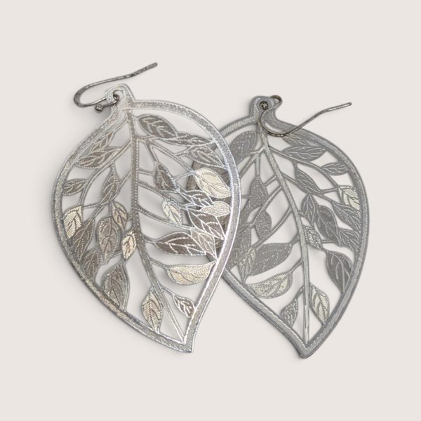 Vintage JC Penney silver-tone cutout leaf dangle earrings with intricate filigree texture.