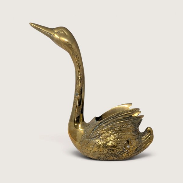 A large vintage solid brass swan planter with a long curved neck, polished golden body, and detailed feather texture on the wings.