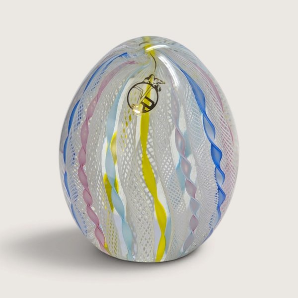 A vintage Vecchia Murano hand-blown glass paperweight egg featuring vertical white latticino lace and colorful twist ribbons with a VR sticker on a neutral background.   