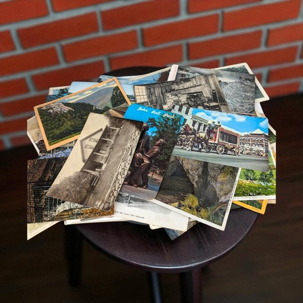 A scattered pile of approximately 40 vintage postcards featuring various travel scenes, historical buildings, landscapes, and monuments in both color and black and white.