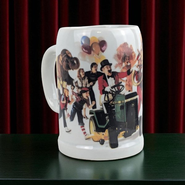 A white ceramic advertising mug featuring a colorful 1980s circus scene with a John Deere tractor, a ringmaster, an elephant, and clowns.