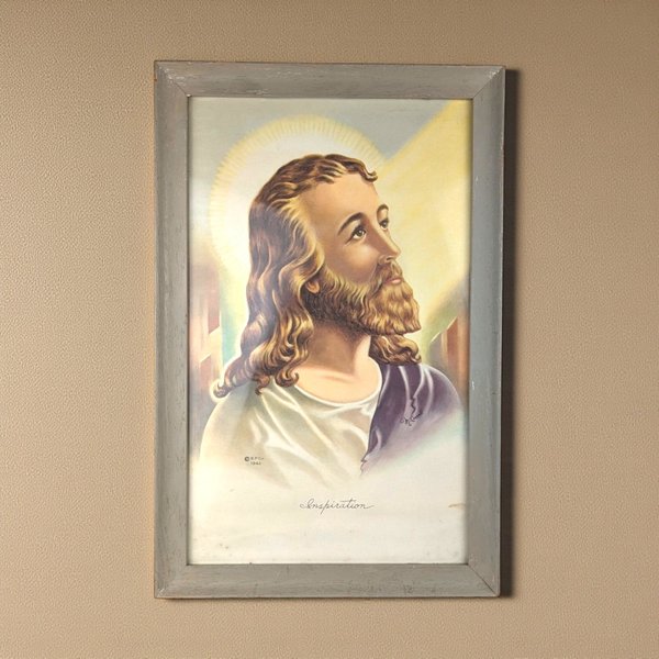 A vertical lithograph of Jesus Christ titled Inspiration in a weathered gray wood frame. The portrait features warm yellow light, a soft halo, and a purple robe against a cream background. The texture of the aged paper and wood grain is visible.