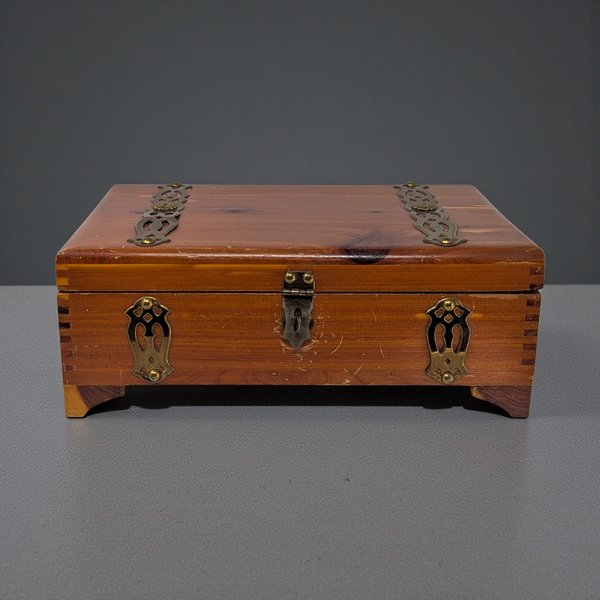 A rectangular wooden box with a smooth, polished finish. The wood grain is prominent, showing a warm honey-oak tone. It features a hinged lid and simple, clean lines without ornate carvings or metal hardware on the exterior.
