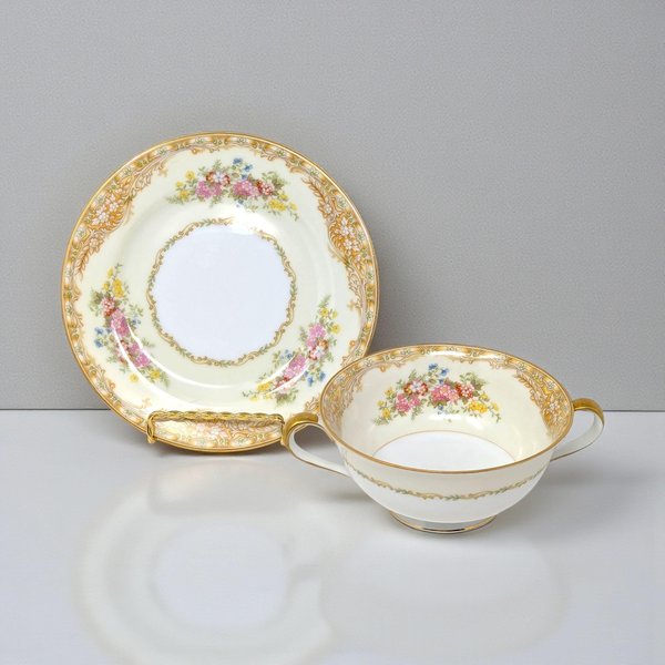 A set of four elegant porcelain soup cups and matching saucers. Each cup features two delicate handles and a wide rim, paired with a circular plate. The porcelain is a bright, polished white with fine gold-line detailing and a smooth, reflective glaze.