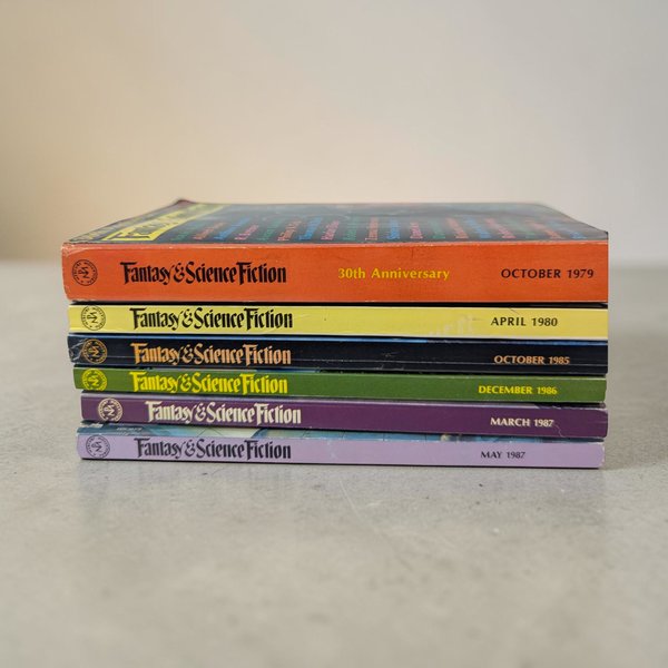 A stack of six small digest-sized magazines with colorful illustrated covers. The texture is aged matte paper with a vertical rectangular silhouette and visible edge wear.