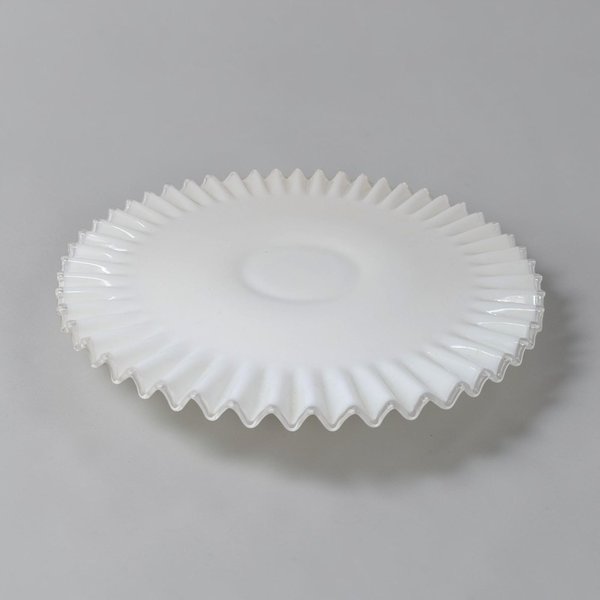 Opaque white milk glass plate with a smooth center and wide, deeply ruffled border edged in a thin ribbon of clear glass. The silhouette is low and circular with a repetitive, undulating texture along the perimeter.