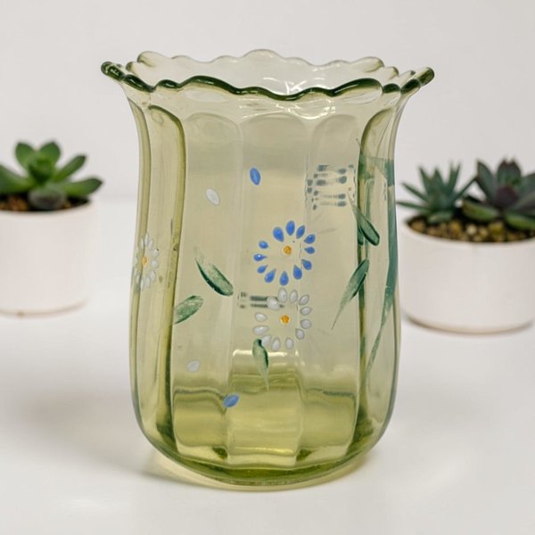 Scalloped rim green glass vase with vertical ribbing and hand-painted blue and white flowers with green leaves.