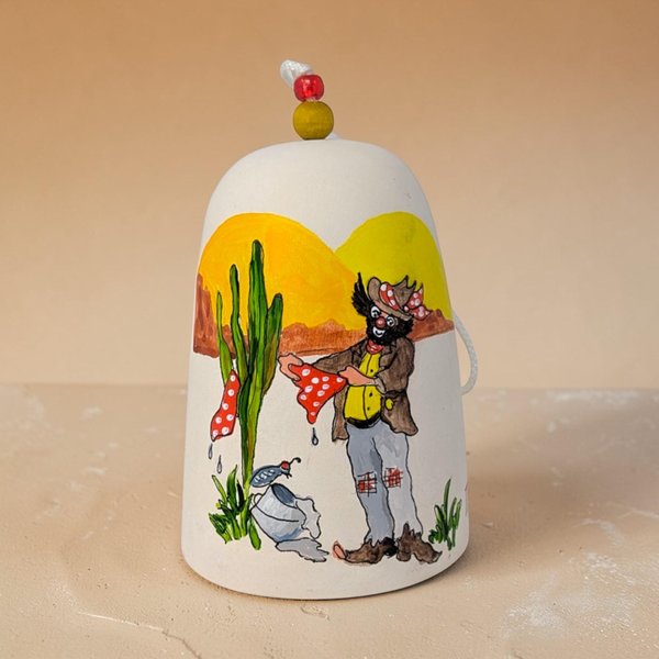 A hand-painted ceramic bell featuring a clown figure in cowboy gear. The clown wears a tan western hat, a red neckerchief, and a yellow suit with red polka dots.