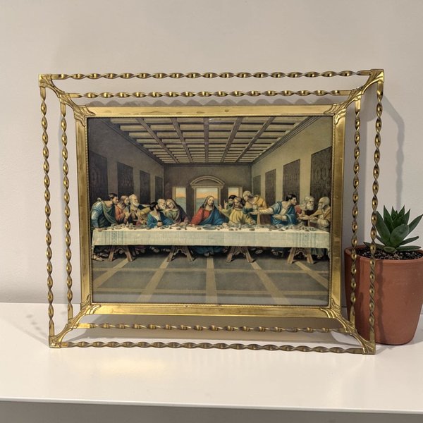 A 12 by 10.5 inch framed Last Supper print with a rectangular silhouette and a metallic twisted wire texture. The gold-tone frame features a unique double-layered openwork design around the central religious lithograph.